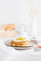 croque Senhora - francês sanduíche com queijo, presunto e ovo em uma prato em uma luz mesa. caseiro café da manhã. vertical Visão foto