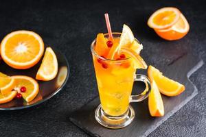 laranja oxicoco efervescente coquetel dentro uma vidro e frutas e bagas perto em uma ardósia em uma Sombrio fundo. caseiro mocktail foto