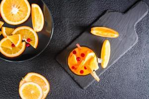 laranja oxicoco efervescente coquetel dentro uma vidro e frutas Próximo para isto em uma Sombrio fundo. caseiro mocktail. topo Visão foto
