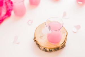 Rosa coquetel dentro uma vidro em uma árvore tronco e papel corações em uma Rosa fundo. bebidas para amantes foto