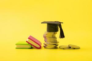 graduado boné com moedas em amarelo fundo. poupança para Educação ou financeiro alfabetização conceito foto