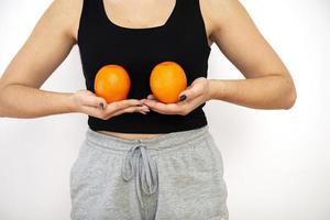mulher segurando duas laranjas na frente dos seios, conceito de conscientização do câncer de mama foto