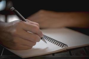 mão segurando uma caneta em um caderno foto