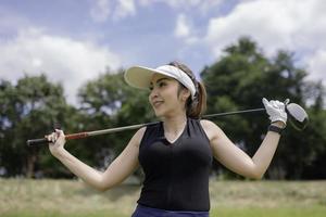 retrato do jogador de golfe ásia mulher segurando golfe madeira às a país clube, feliz mulher conceito, colocar golfe em PIN foto