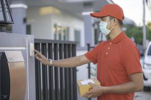 ásia Entrega homem vestem protetora mascarar dentro vermelho uniforme, on-line Comida e produtos Entrega conceito, novo normal dentro covid-19 foto