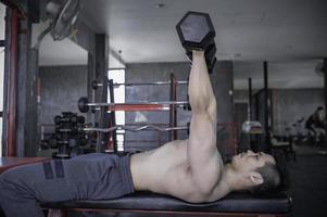 retrato do grande músculo do homem asiático na academia, tailândia, treino para uma boa saúde, treinamento com peso corporal, fitness no conceito de academia foto