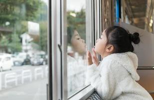 pequeno menina olhando através janela. ela viaja em uma trem. foto