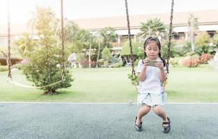 fofa menina aluna jogar inteligente telefone em balanço foto