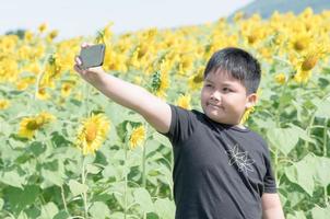 fofa gordo Garoto levando uma selfie com inteligente telefone foto