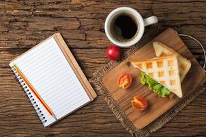 sanduíche e café com em branco caderno foto