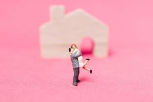 casal em miniatura com casas em um fundo rosa, conceito de dia dos namorados foto