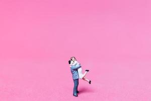 casal em miniatura se abraçando em um fundo rosa, conceito de dia dos namorados foto