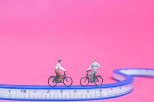 viajantes em miniatura com bicicletas em uma ponte azul em um fundo rosa foto