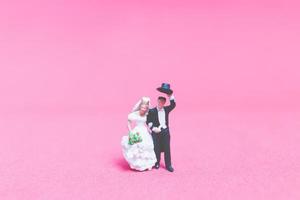 casamento em miniatura, uma noiva e um noivo em um fundo rosa foto