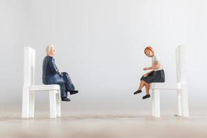 Empresários em miniatura sentados em cadeiras com um fundo desfocado foto
