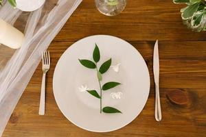 uma verde raminho com folhas em uma servindo prato em a festivo mesa. Casamento ou aniversário decoração foto
