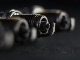 um close-up das velas de ignição com defeito, contra um fundo preto foto