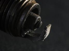 uma foto macro dos contatos de uma vela de ignição de carro com defeito em um fundo preto