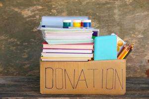 doação caixa com escola suprimentos em velho de madeira fundo.