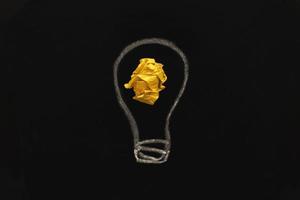 lâmpada de papel amarelo amassado como uma ideia criativa de conceito em um fundo de quadro-negro foto