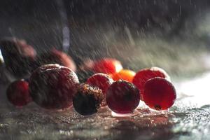 fechar-se congeladas bagas em a vidro com reflexão . congeladas bagas em uma Sombrio fundo macro. cranberries amoras e cerejas foto