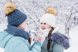 dois sorridente meninas dentro caloroso roupas conheceu dentro uma Nevado parque. inverno anda em, estilo de vida foto