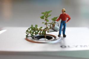 uma miniatura figura do uma agricultor rega uma em vaso plantar dentro a Formato do a analógico Câmera lente. foto