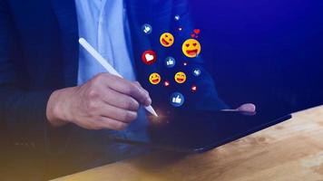 social meios de comunicação e conectados digital conceito, homem de negocios usando computador portátil enviando emojis com social meios de comunicação. foto