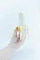 a descascado banana dentro uma fêmea mão segurando em branco fundo,banana frutas foto