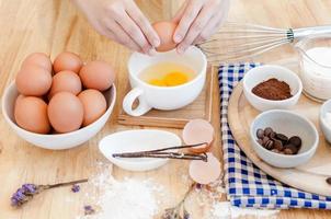 homem dentro a cozinha cozinhando uma massa. mãos rompe a ovo para dentro uma tigela ,mãos derramando mordido ovo ,cozimento conceito foto