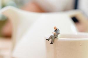 empresário em miniatura sentado em uma xícara de chá
