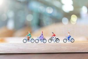 pessoas em miniatura pedalando em uma ponte de madeira, conceito de saúde foto