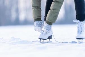 amarrando os cadarços de patins de inverno em um lago congelado, patinando no gelo foto