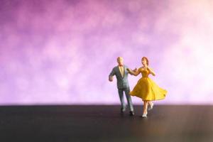 casal em miniatura dançando com um fundo colorido bokeh foto