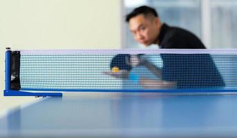 masculino jogando tênis de mesa com raquete e bola em um ginásio esportivo foto