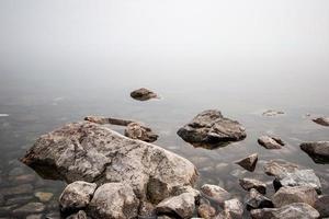 pedras em a lago dentro a névoa. grande e pequeno pedras. a água é transparente e debaixo a água você pode Vejo pedras cheio com lodo. cópia de espaço. foto