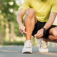 jovem atleta homem amarrar corrida sapatos dentro a parque ar livre, masculino corredor pronto para corrida em a estrada fora, ásia ginástica caminhando e exercício em trilha dentro manhã. bem estar e esporte conceitos foto