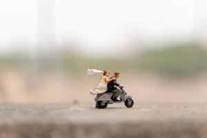 casal em miniatura andando de moto em um jardim foto