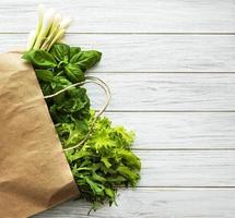 verduras frescas em um saco de papel em um fundo de madeira foto