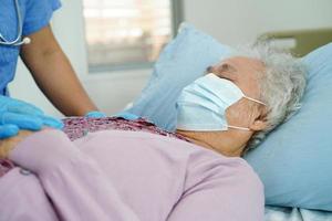 médico verifica paciente idosa asiática usando uma máscara para proteger o coronavírus covid. foto