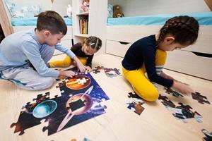 crianças conectando peças de quebra-cabeça em um quarto infantil no chão de casa. diversão em família atividade lazer. foto