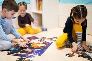 crianças conectando peças de quebra-cabeça em um quarto infantil no chão de casa. diversão em família atividade lazer. foto