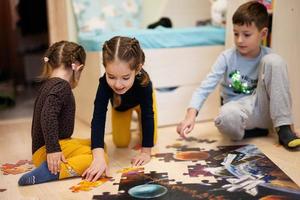 crianças conectando peças de quebra-cabeça em um quarto infantil no chão de casa. diversão em família atividade lazer. foto