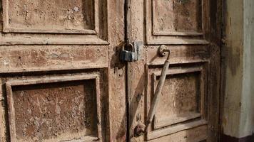 a trava em a velho de madeira porta fechar-se. ferrugem em a metal trancar. descamação Castanho pintura em a velho porta. antigo textura. foto