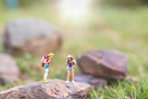 viajantes em miniatura com mochilas caminhando na natureza, conceito de viagem e aventura foto