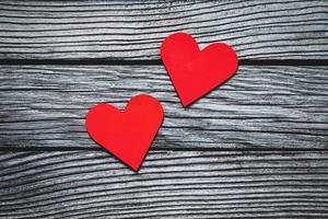 dois vermelho papel corações em cinzento texturizado de madeira fundo foto