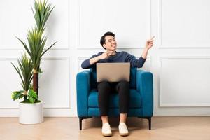 retrato do ásia homem sentado em sofá às casa foto