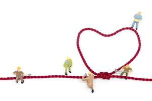 trabalhadores em miniatura construindo uma corda em forma de coração em um fundo branco foto