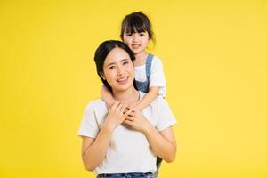 imagem de mãe asiática e filha posando em um fundo amarelo foto