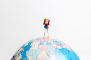 pessoa em miniatura em um globo com um fundo branco, conceito de viagens foto